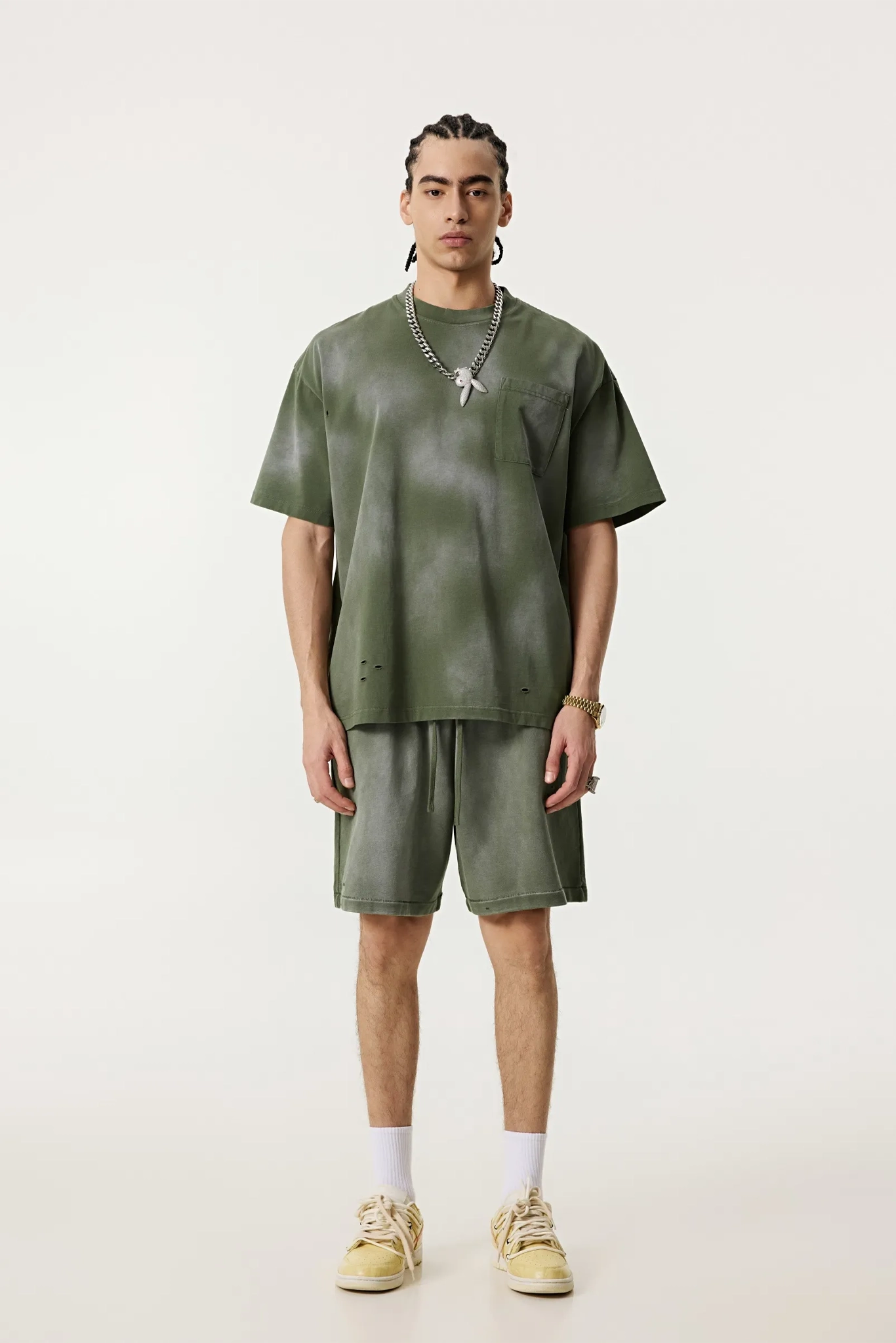 Person wearing a green outfit with shorts and a t-shirt on a white background