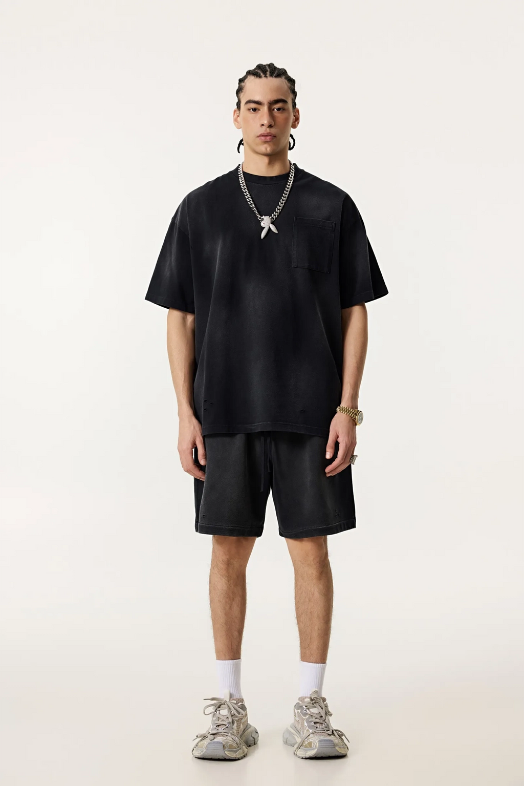 Person wearing a black outfit with shorts and sneakers on a white background