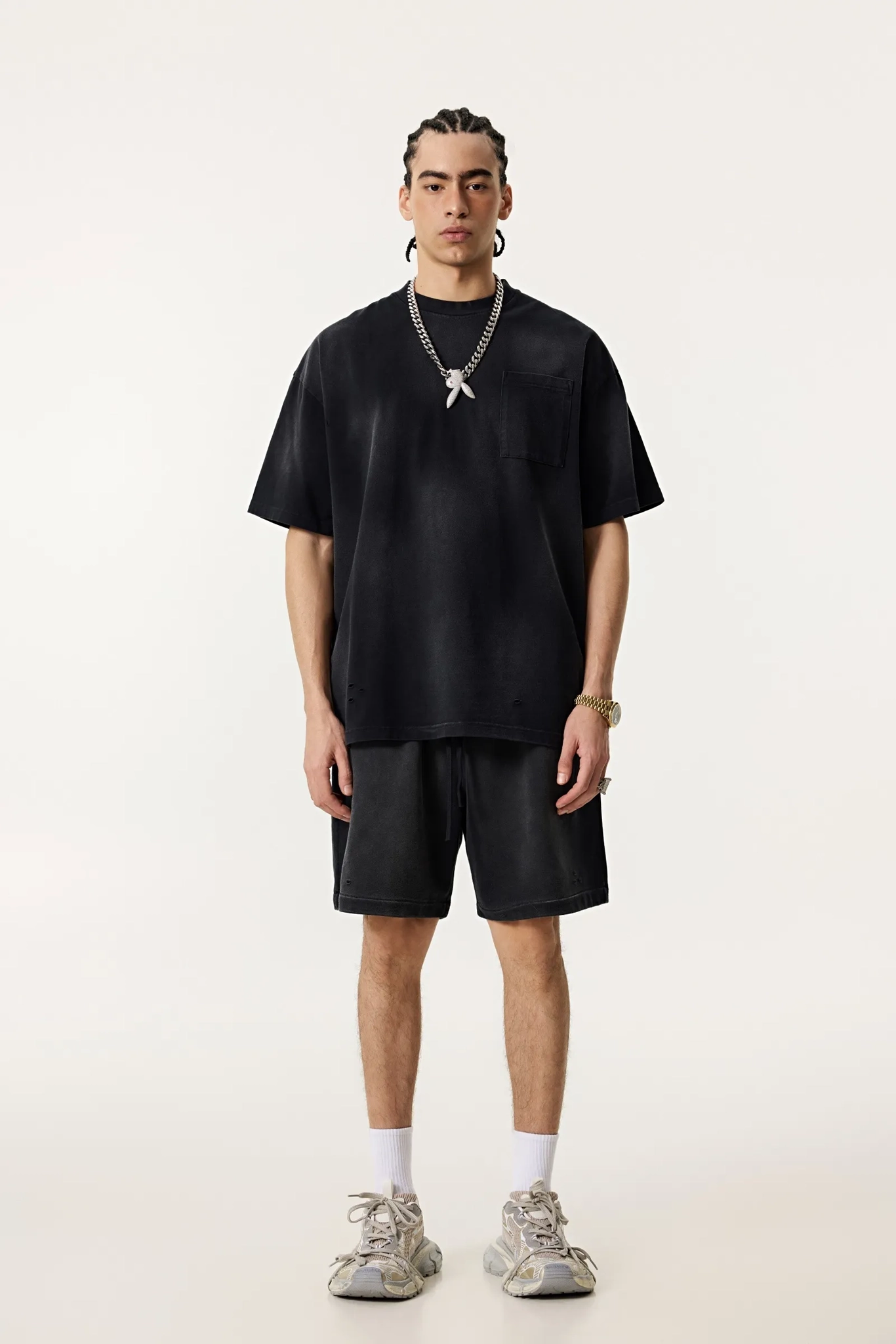 Person wearing a black outfit with shorts and sneakers on a white background