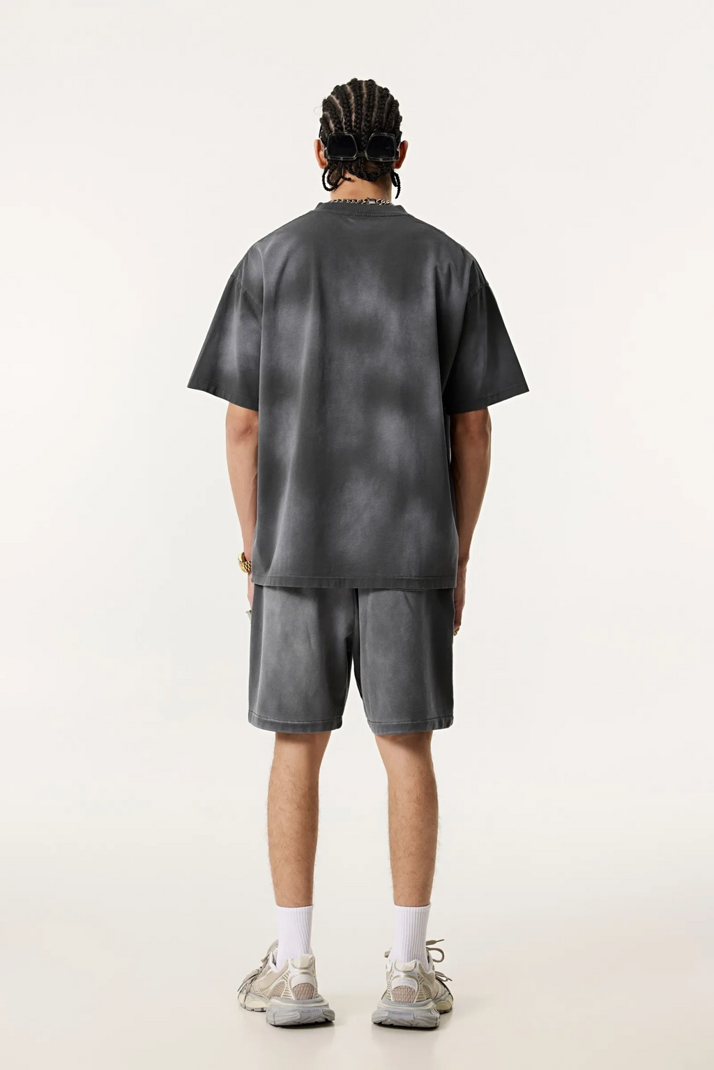 Person wearing a dark gray t-shirt and shorts set on a white background