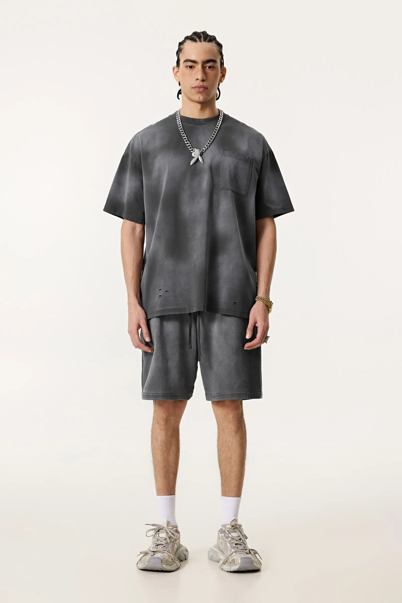 Person wearing a gray outfit with shorts on a white background