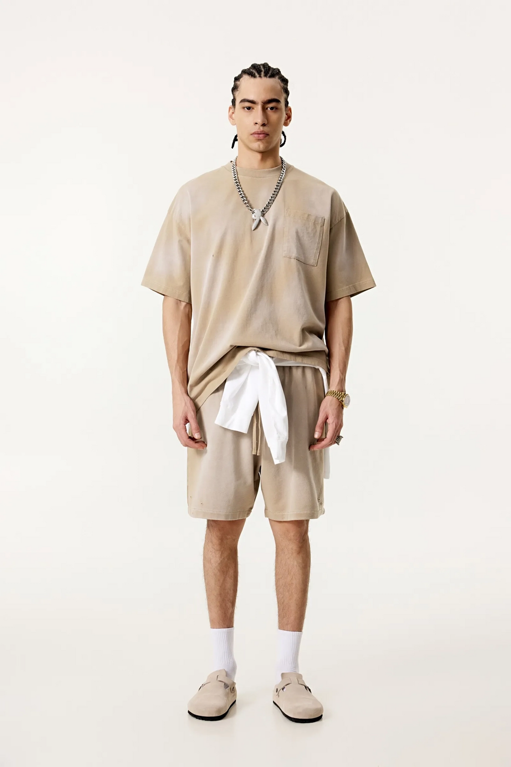 Person wearing a beige outfit with shorts and a t-shirt on a white background