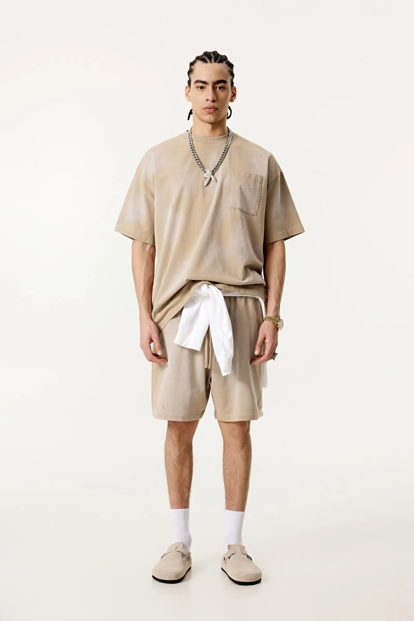 Person wearing a beige outfit with shorts and a t-shirt on a white background