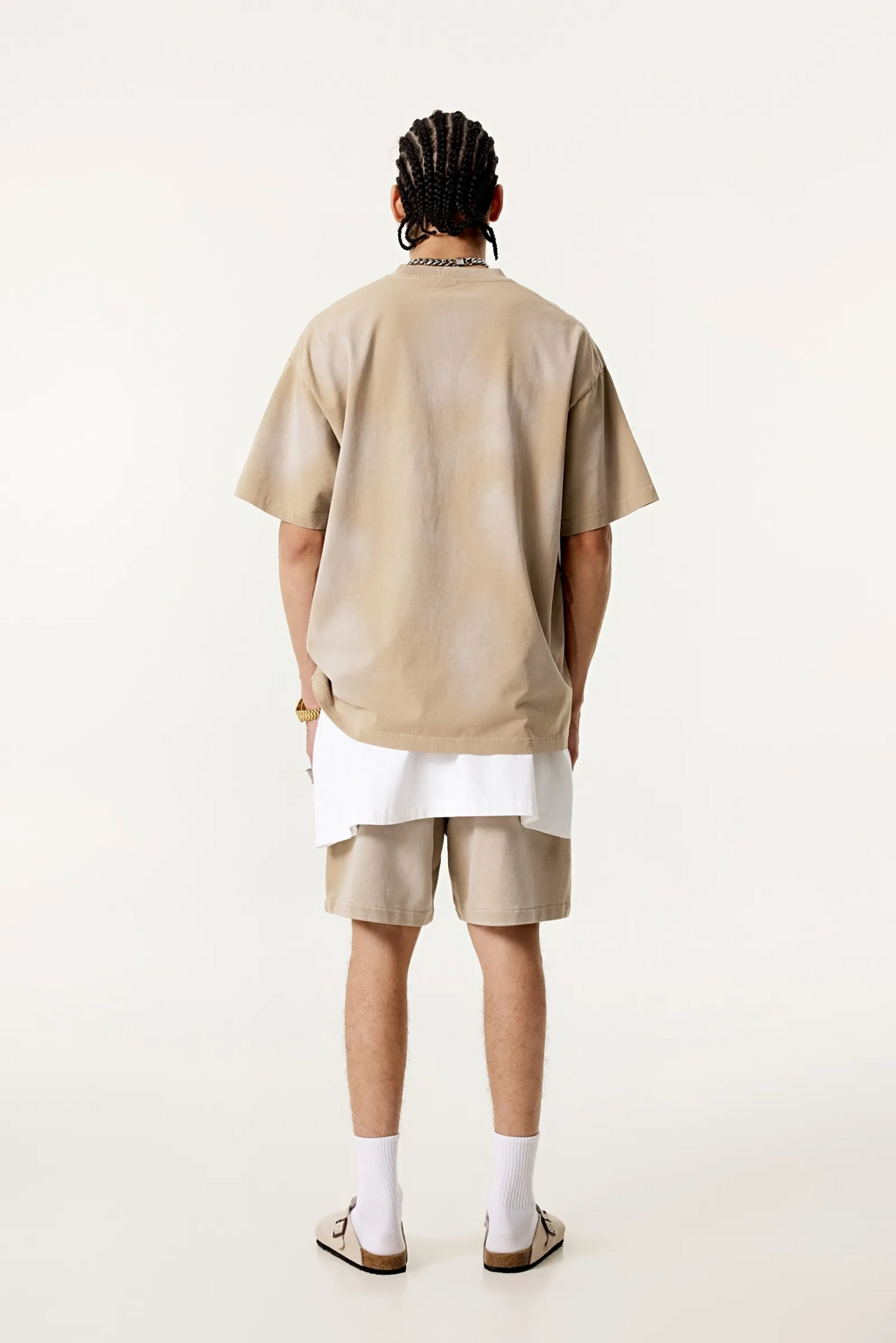 Person wearing a beige outfit with white socks on a white background