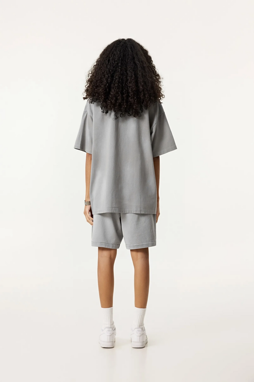 Person wearing a gray outfit with shorts on a white background