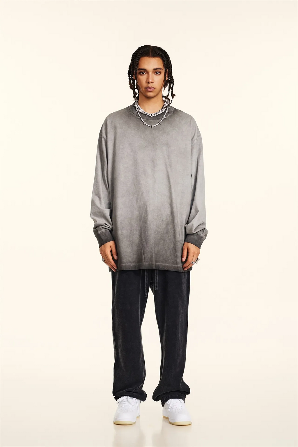 Person wearing a gray oversized sweater and black pants on a beige background
