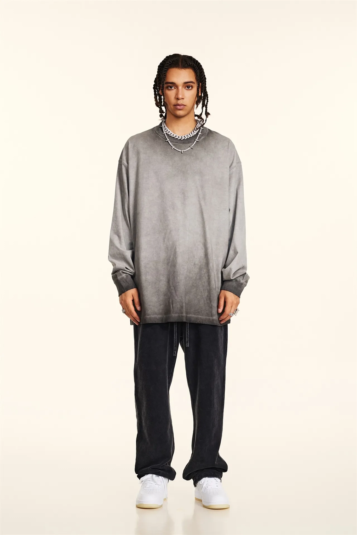 Person wearing a gray oversized sweater and black pants on a beige background