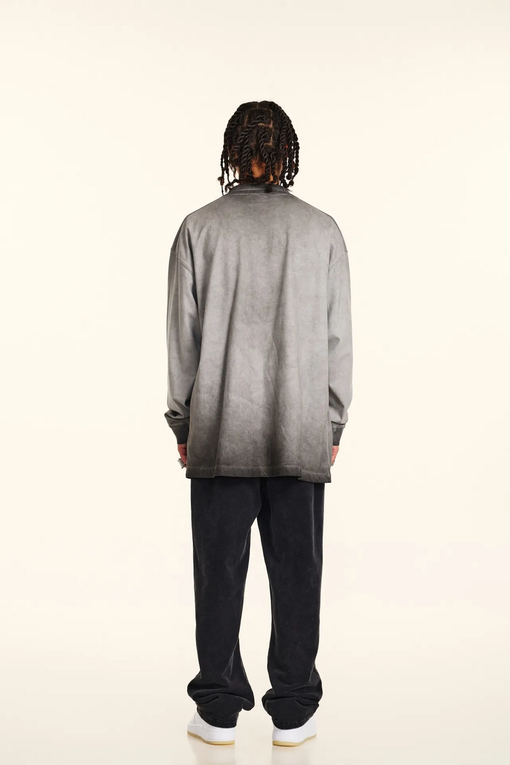Person wearing a gray gradient shirt and black pants on a white background