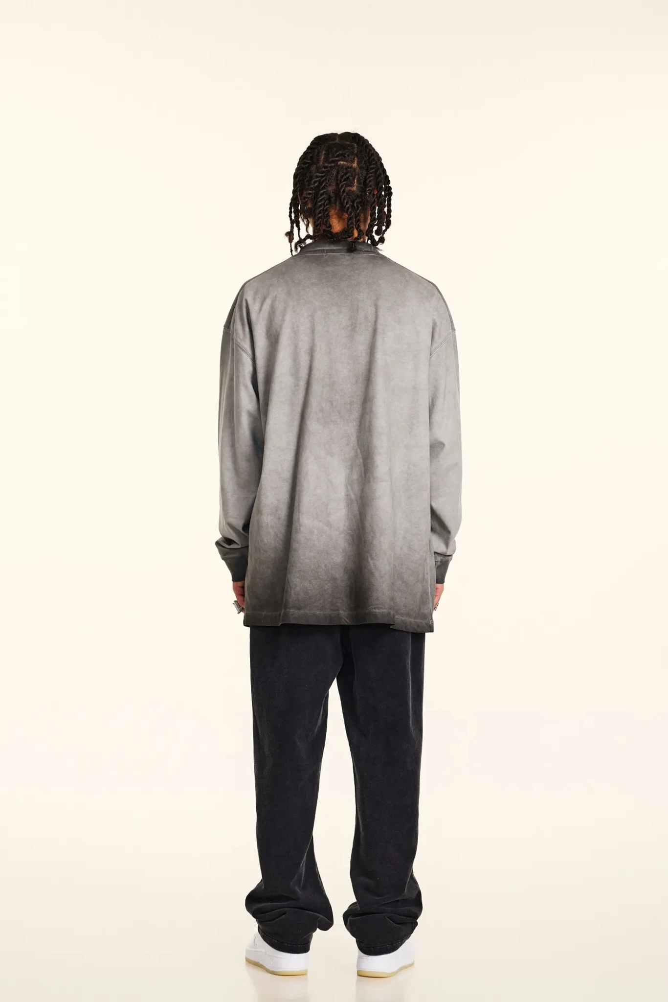 Person wearing a gray gradient shirt and black pants on a white background