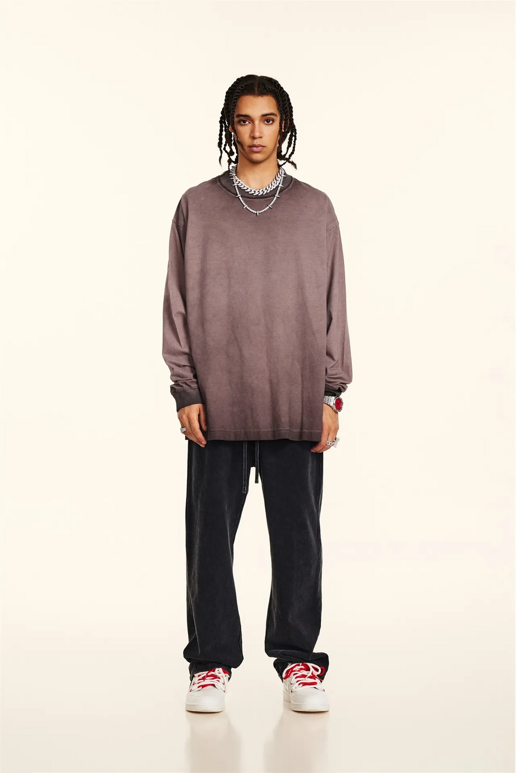 Person wearing a brown oversized sweater, black pants, and white sneakers on a beige background