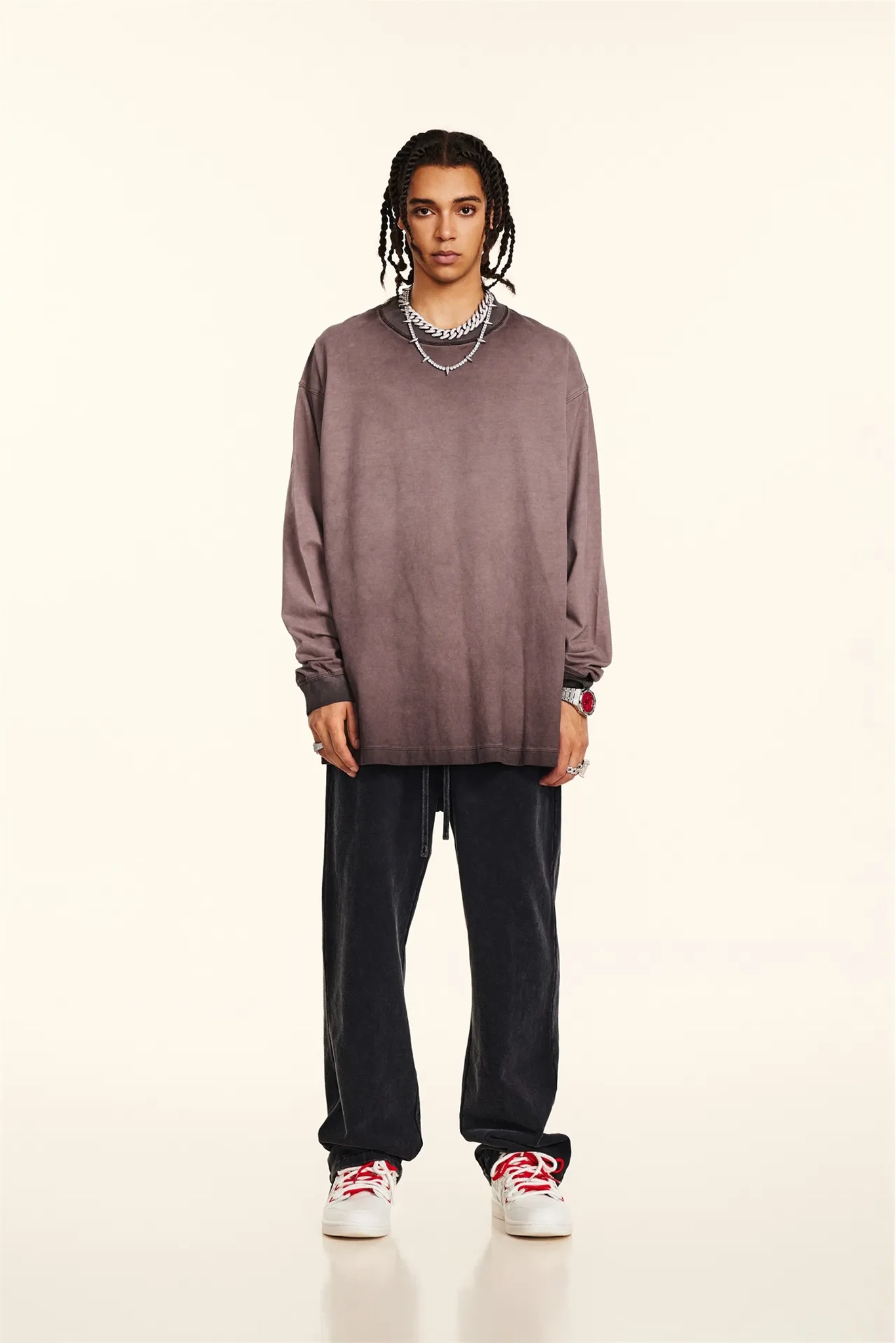 Person wearing a brown oversized sweater, black pants, and white sneakers on a beige background