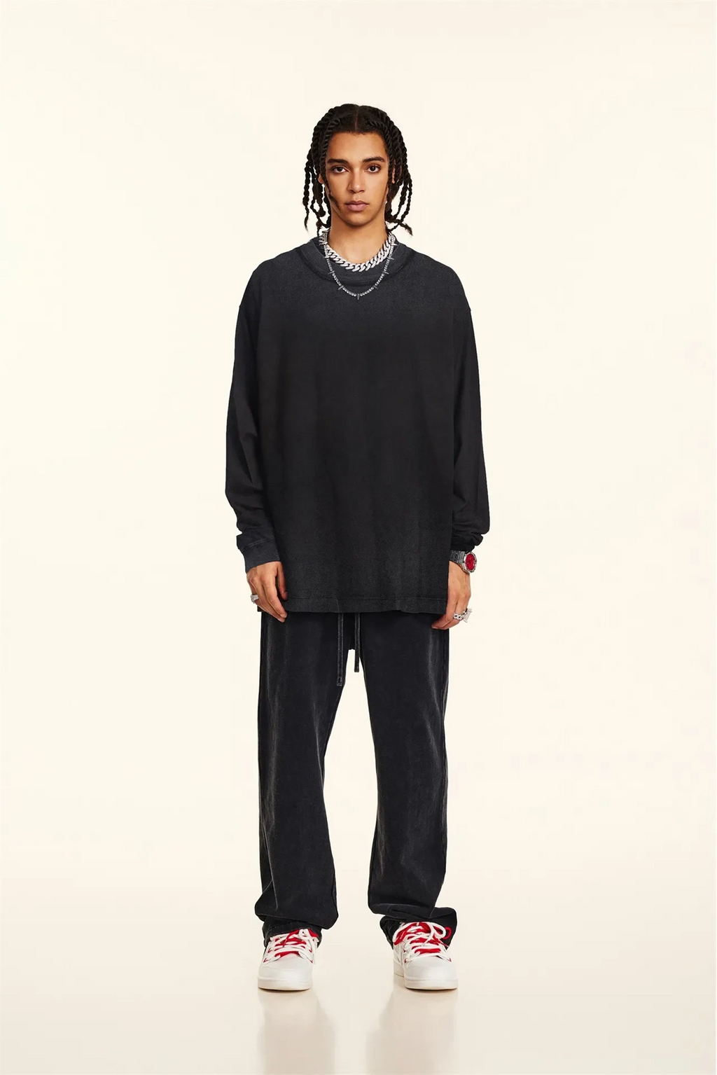 Person wearing a black outfit with white sneakers on a beige background