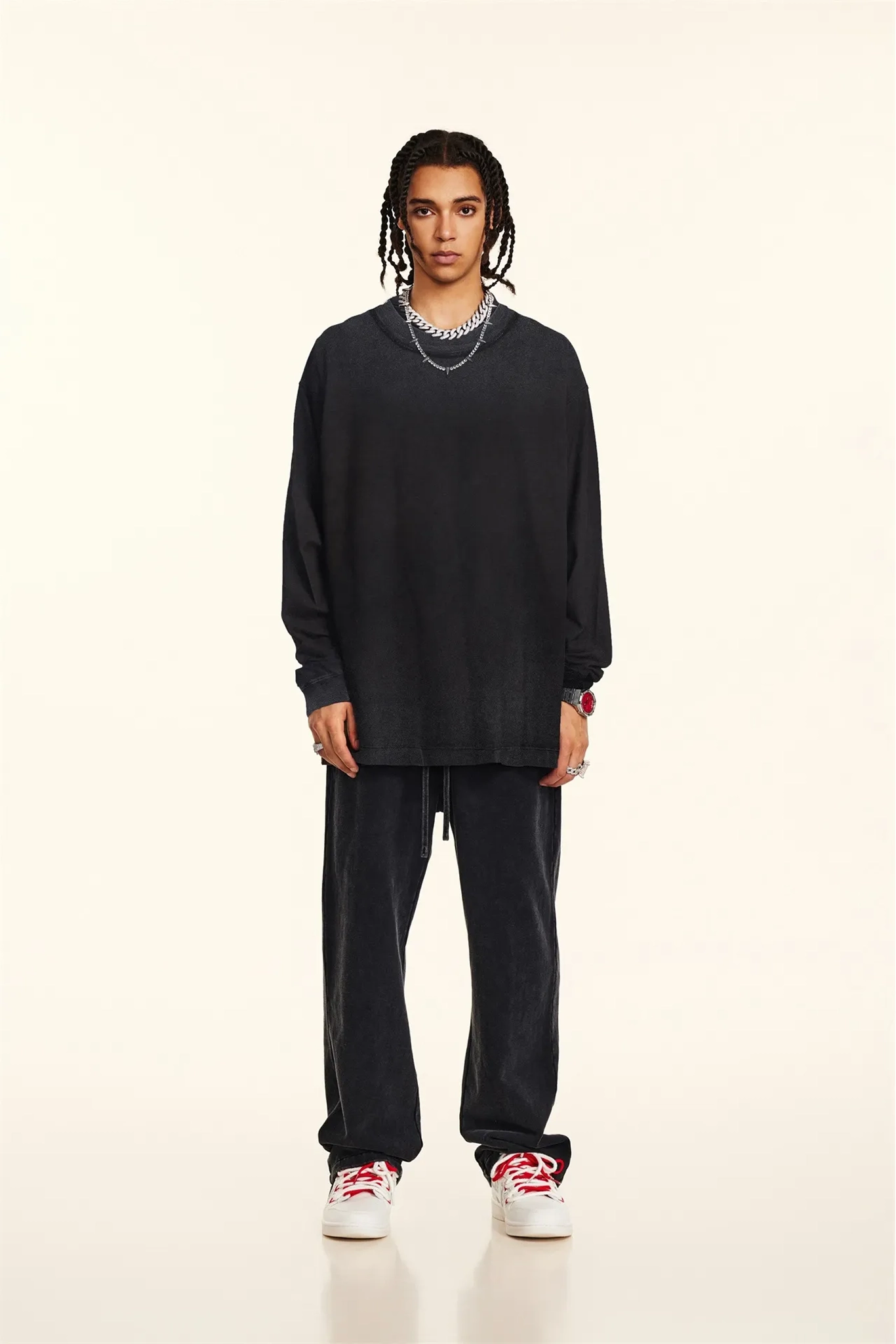 Person wearing a black outfit with white sneakers on a beige background