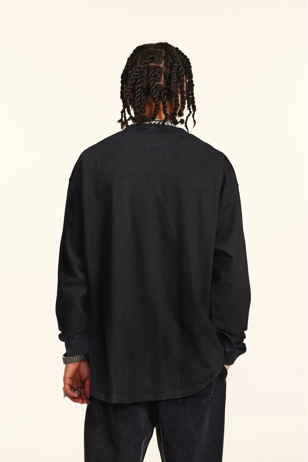 Person wearing a black long-sleeve shirt on a beige background