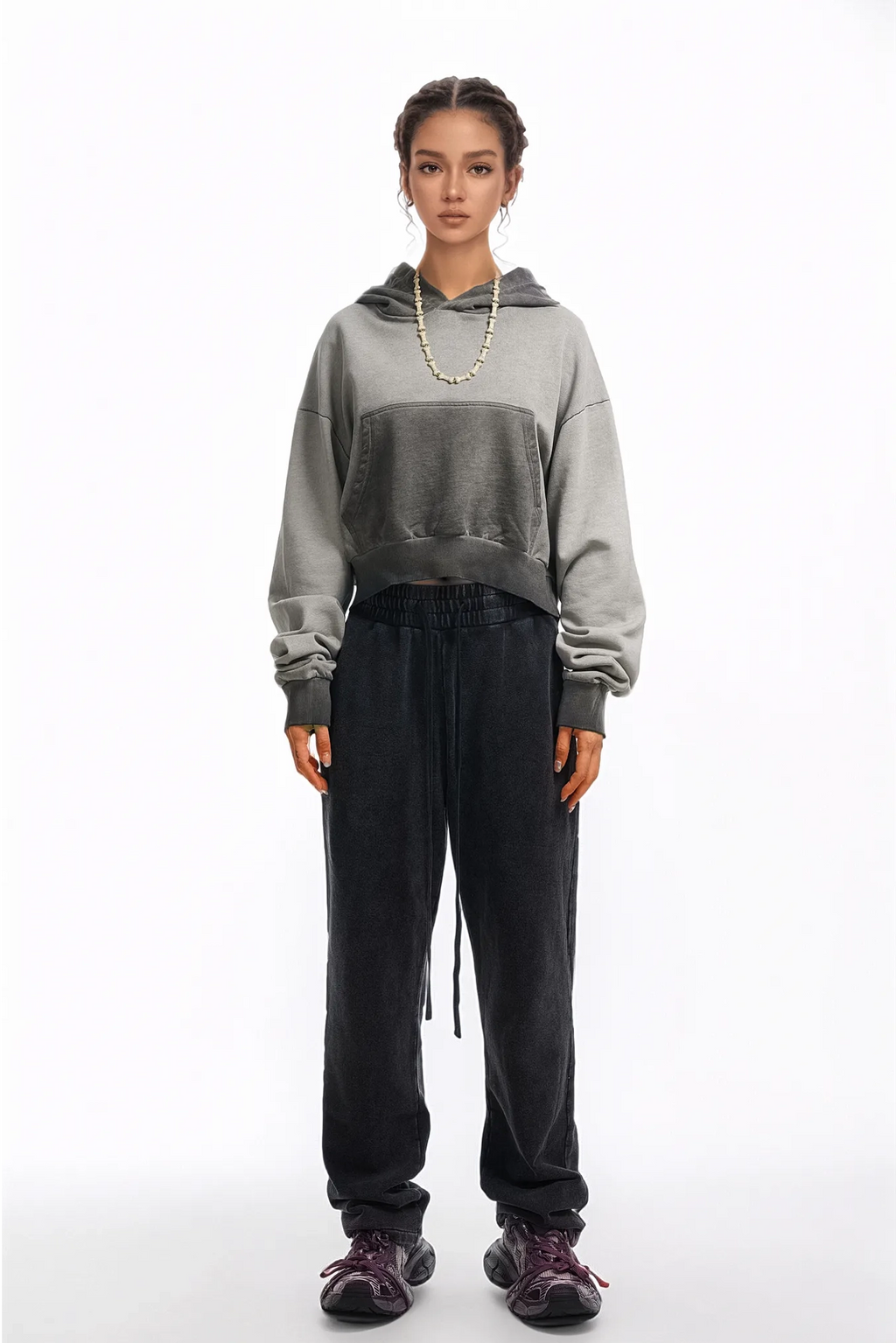 Person wearing a gray hoodie and black pants on a white background