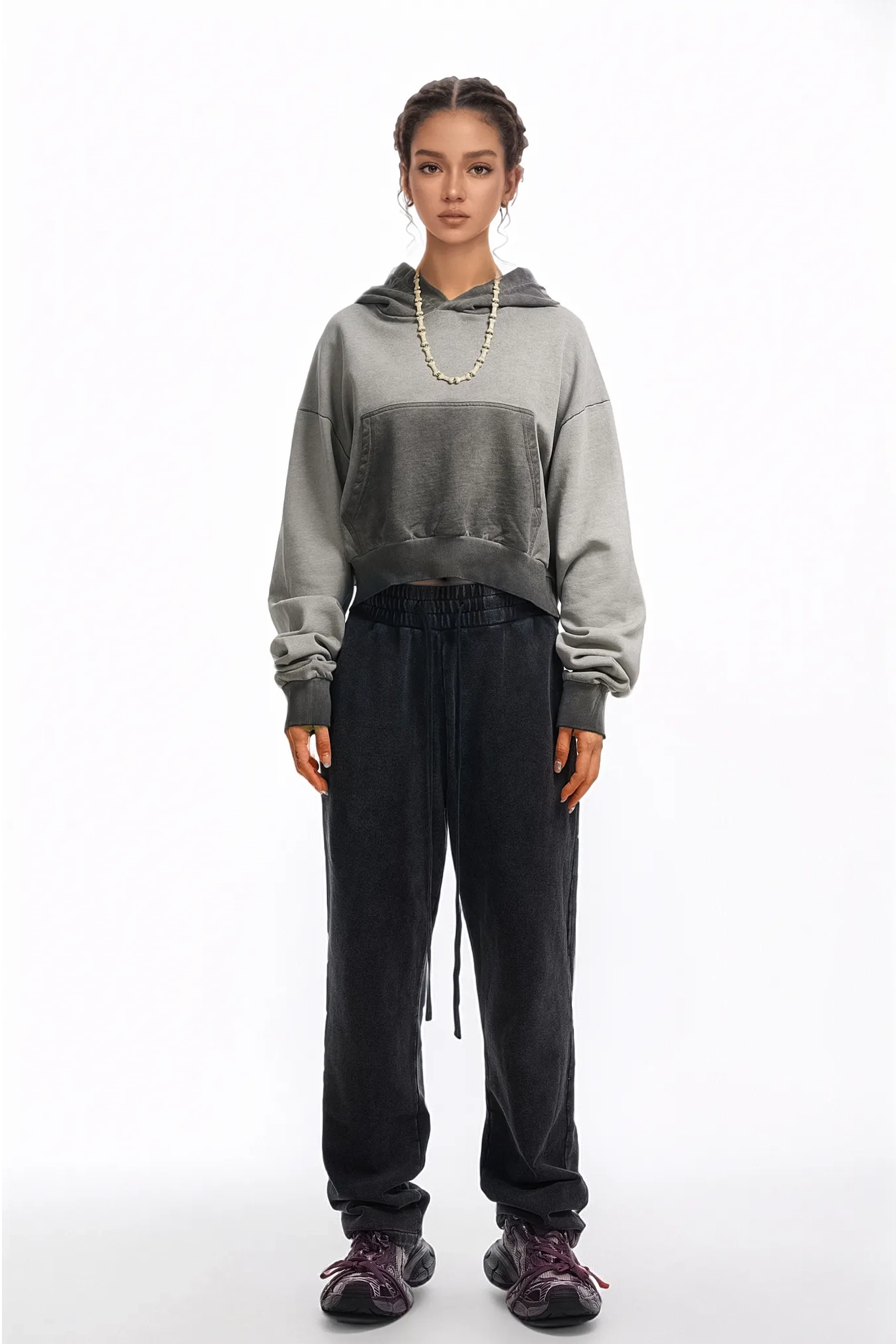 Person wearing a gray hoodie and black pants on a white background