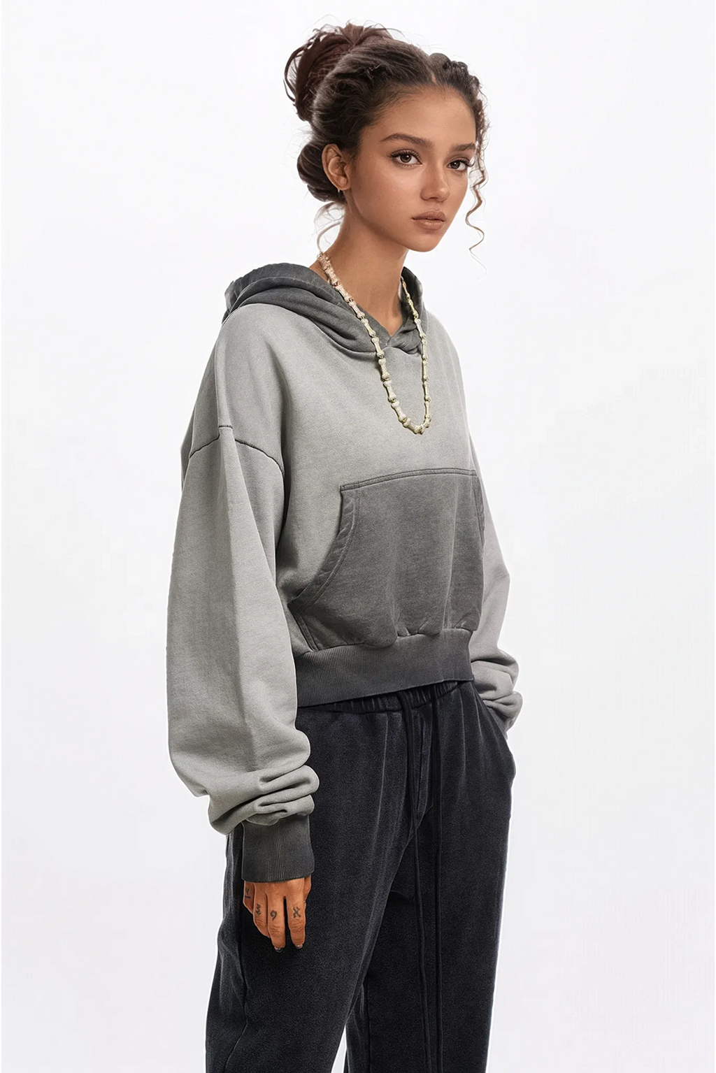 Woman wearing a gray hoodie and black pants on a white background