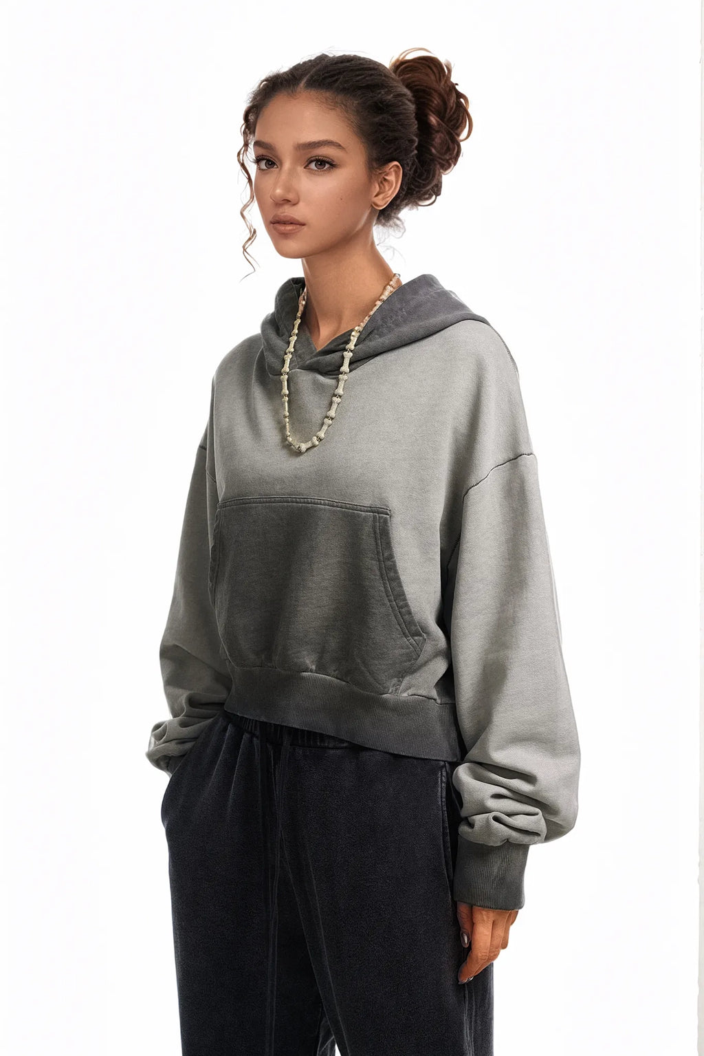 Woman wearing a gray hoodie and black pants on a white background