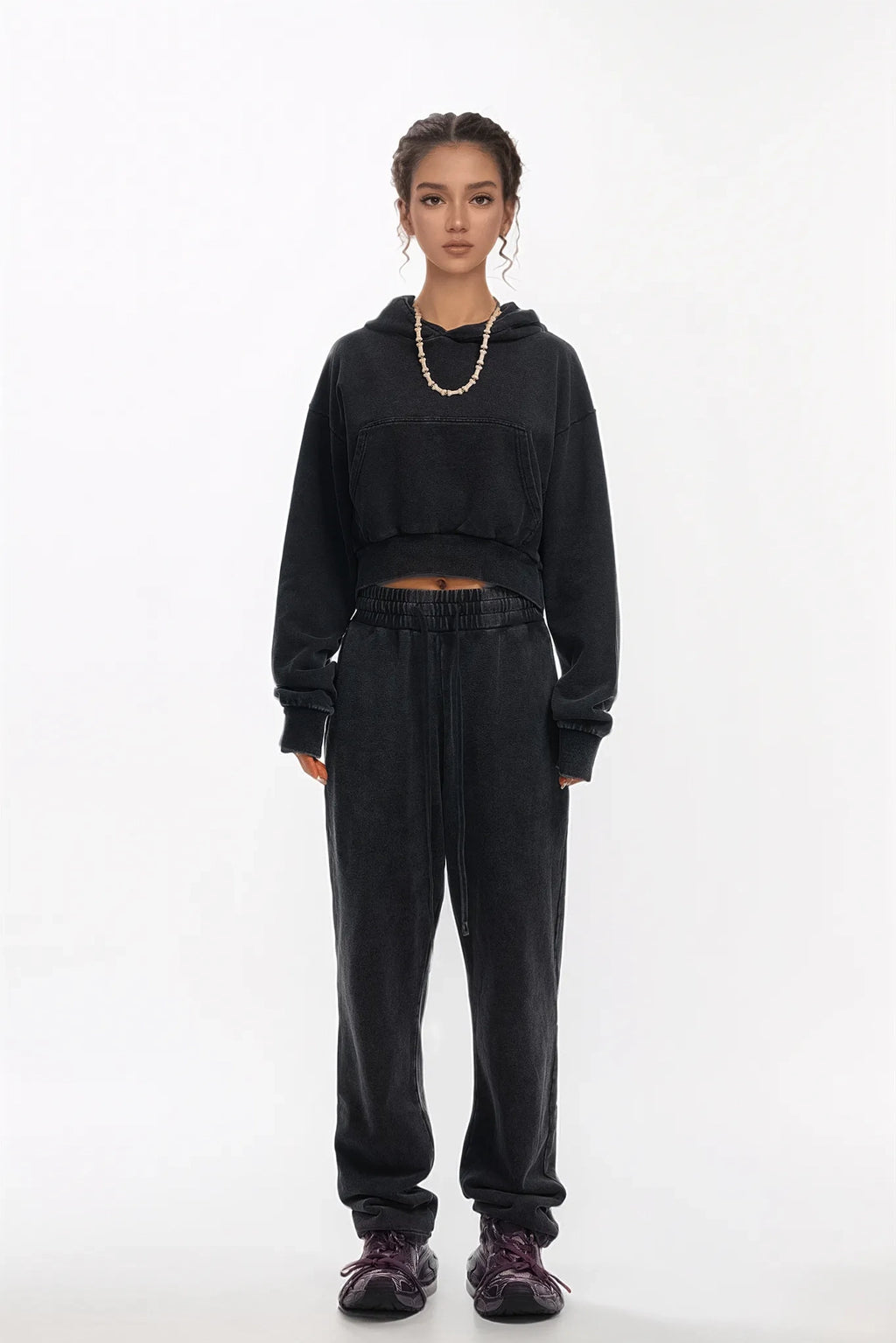 Person wearing a black hoodie and pants on a white background