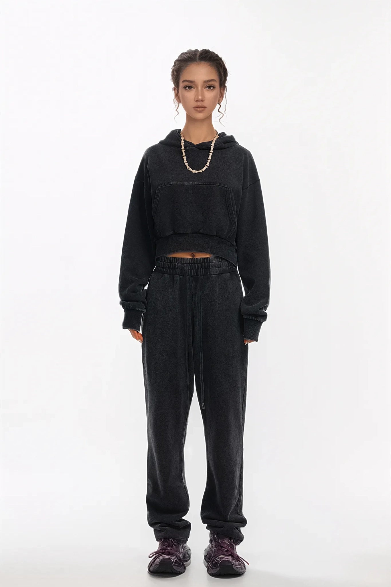 Person wearing a black hoodie and pants on a white background