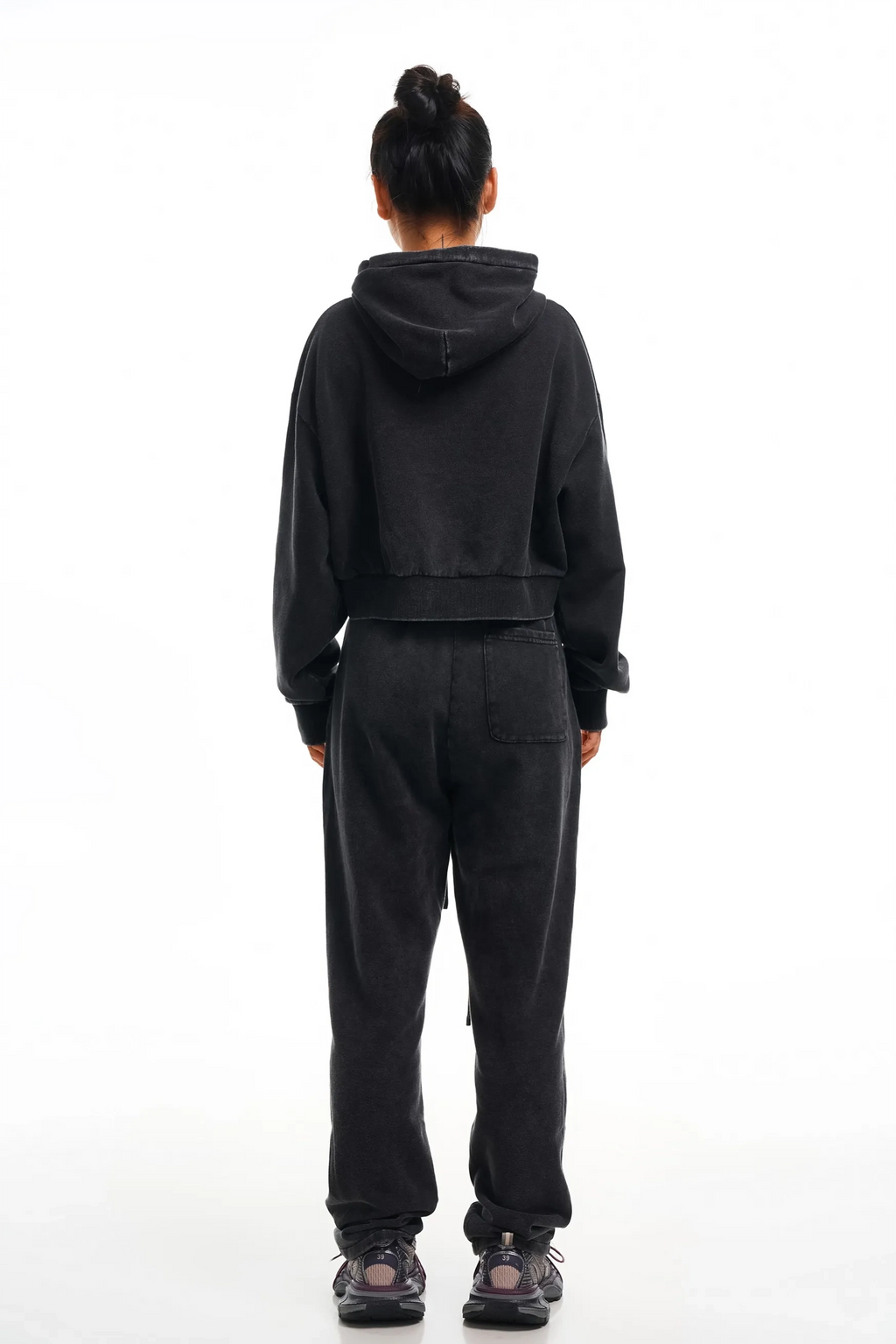 Person wearing a black hoodie and pants set on a white background
