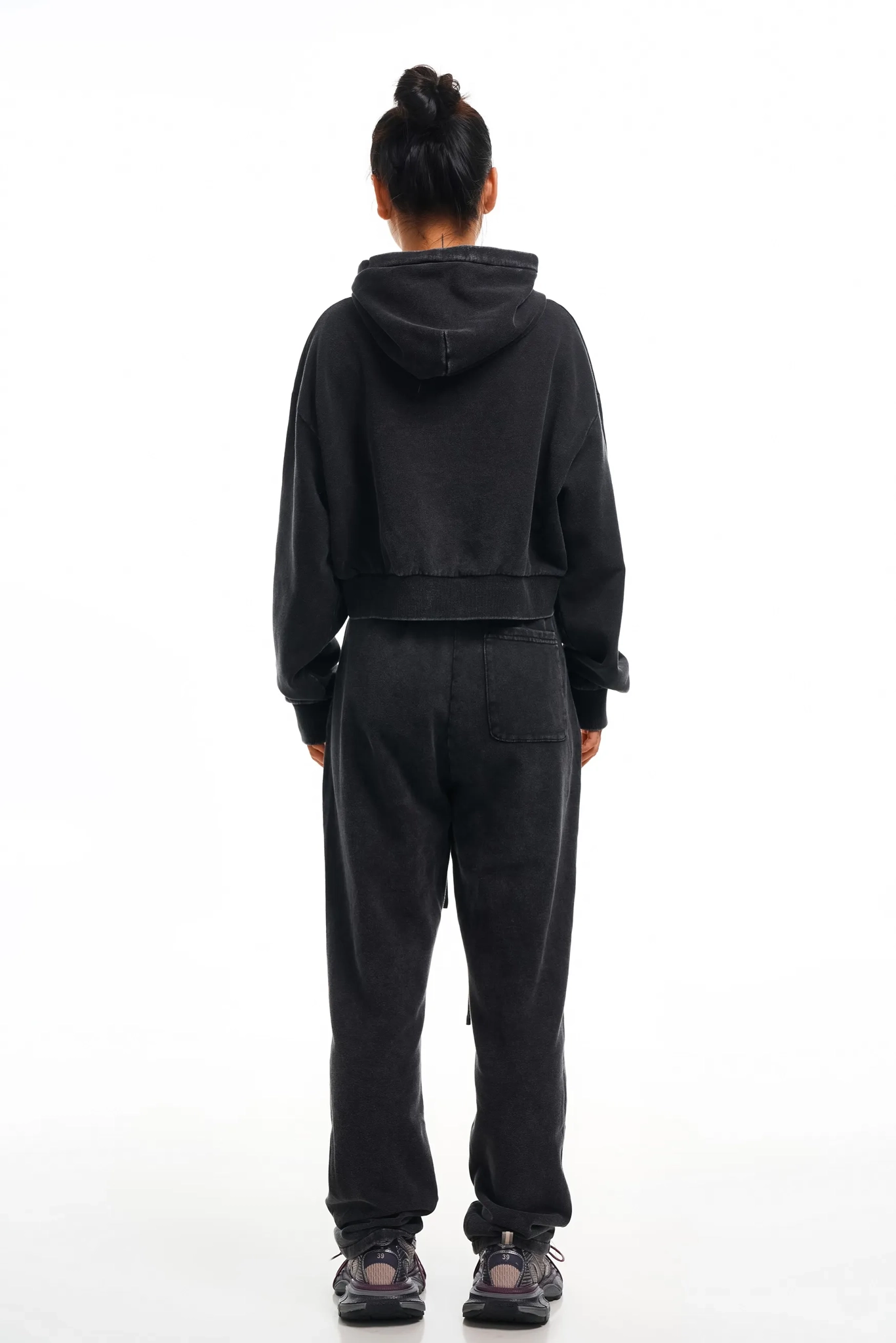 Person wearing a black hoodie and pants set on a white background