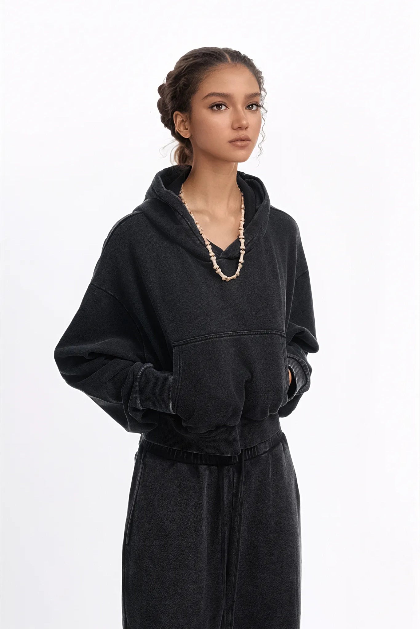 Woman wearing a black hoodie and pants on a white background