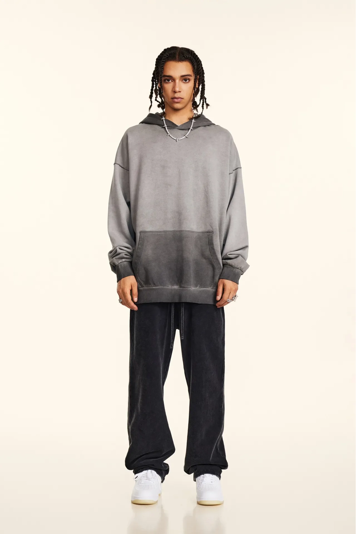 Person wearing a gray hoodie and black pants on a white background