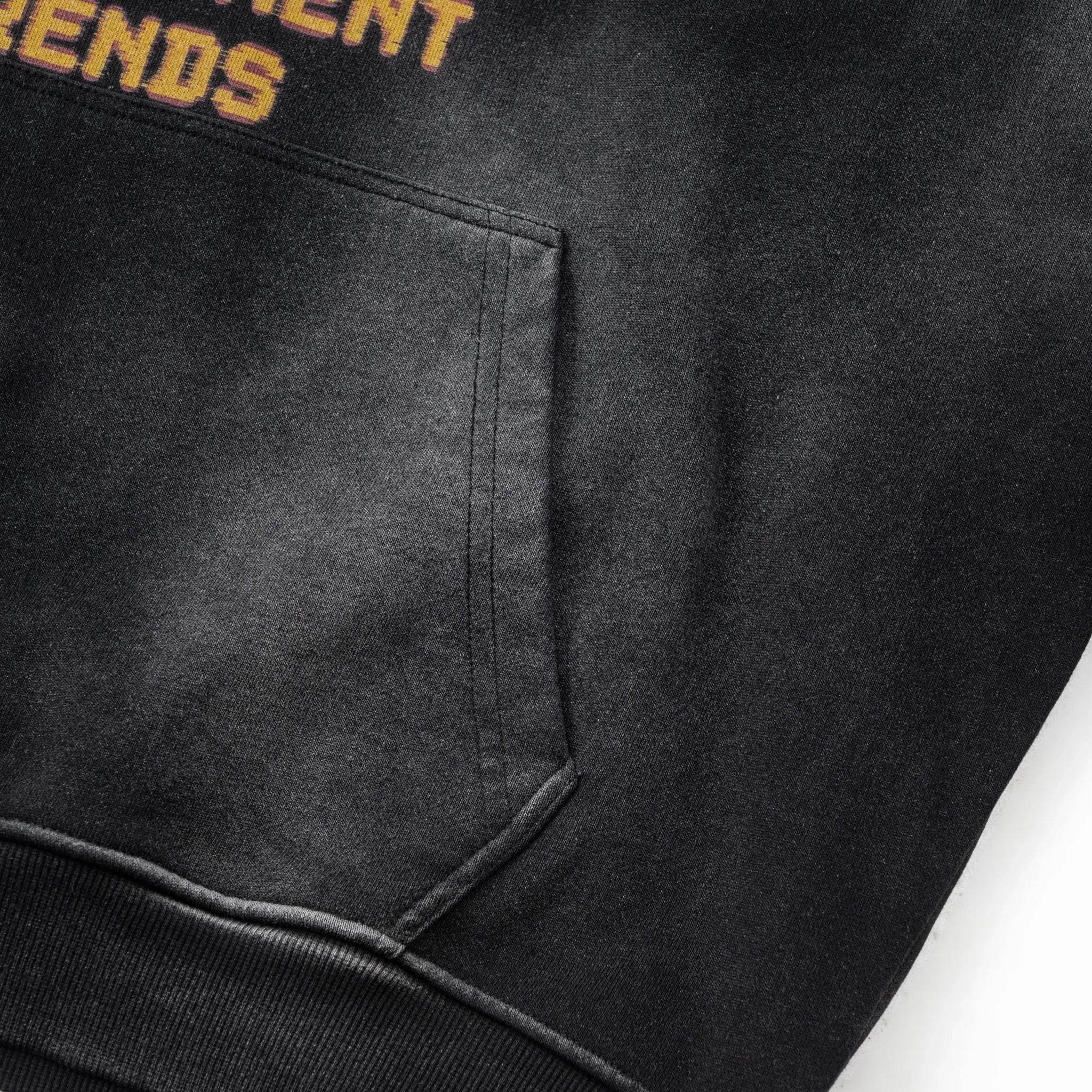 Black hoodie with text on the chest pocket and sleeve, close-up view.