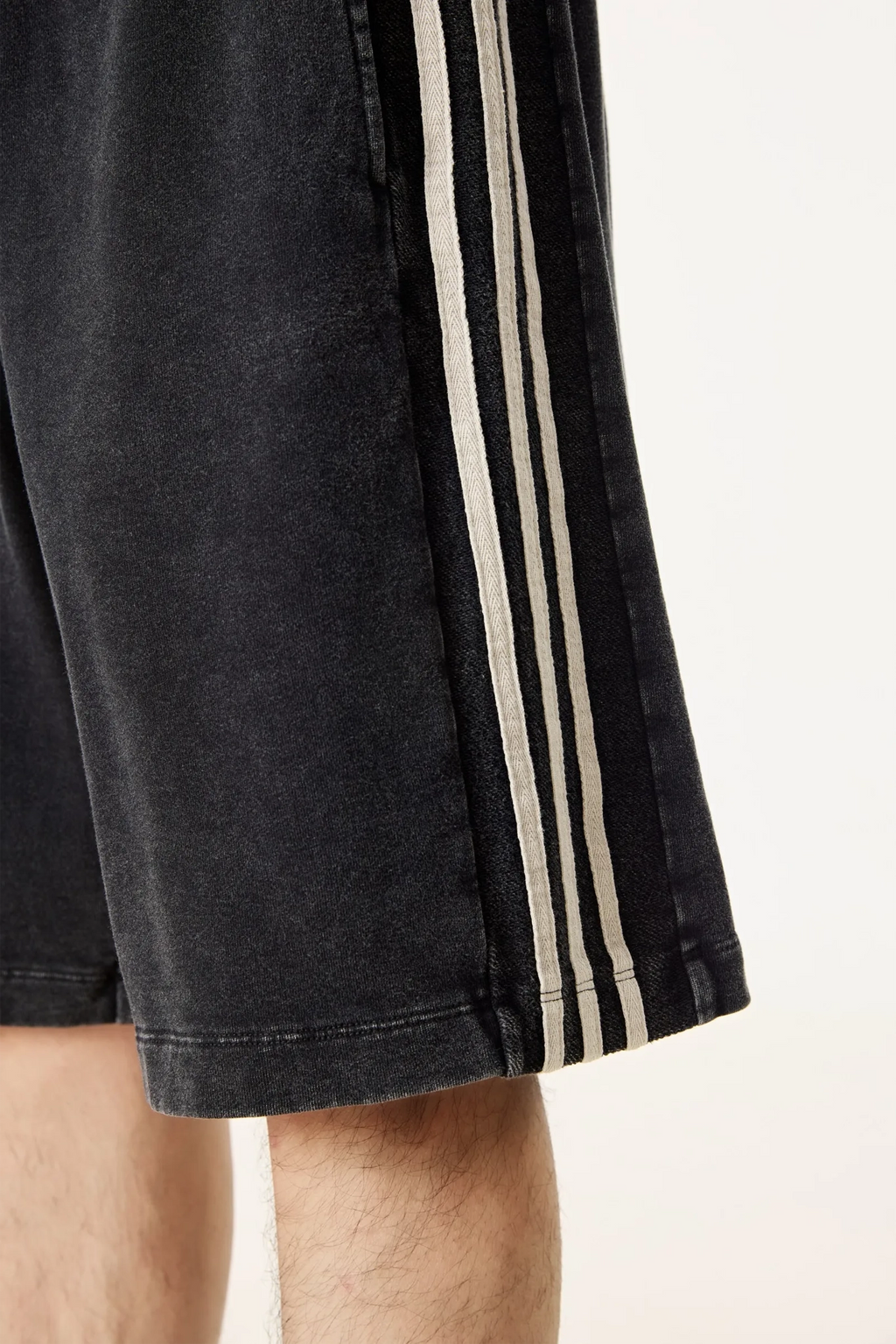 Black shorts with three white stripes on a light background