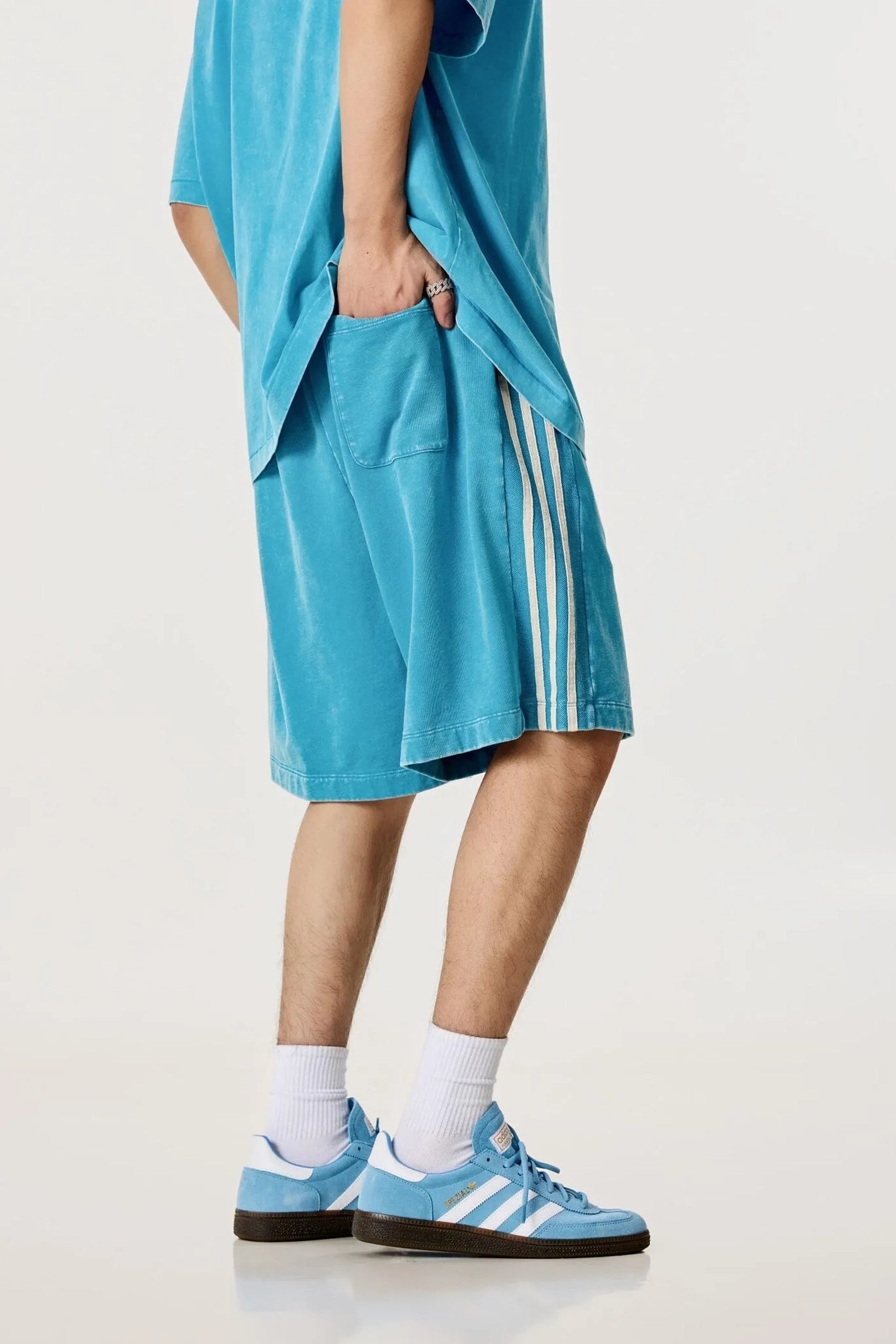 Person wearing a blue outfit with Adidas shorts on a white background