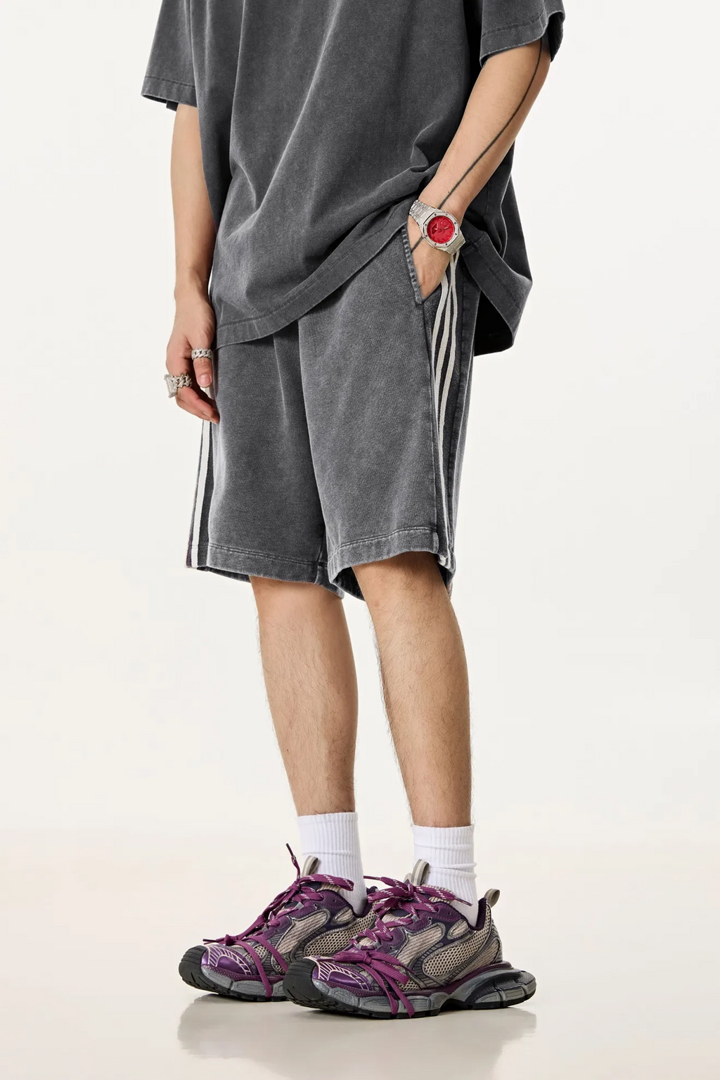Person wearing a gray oversized t-shirt, shorts, and purple sneakers on a white background