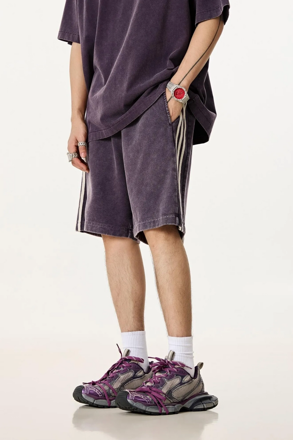 Person wearing a purple outfit with shorts and sneakers on a white background