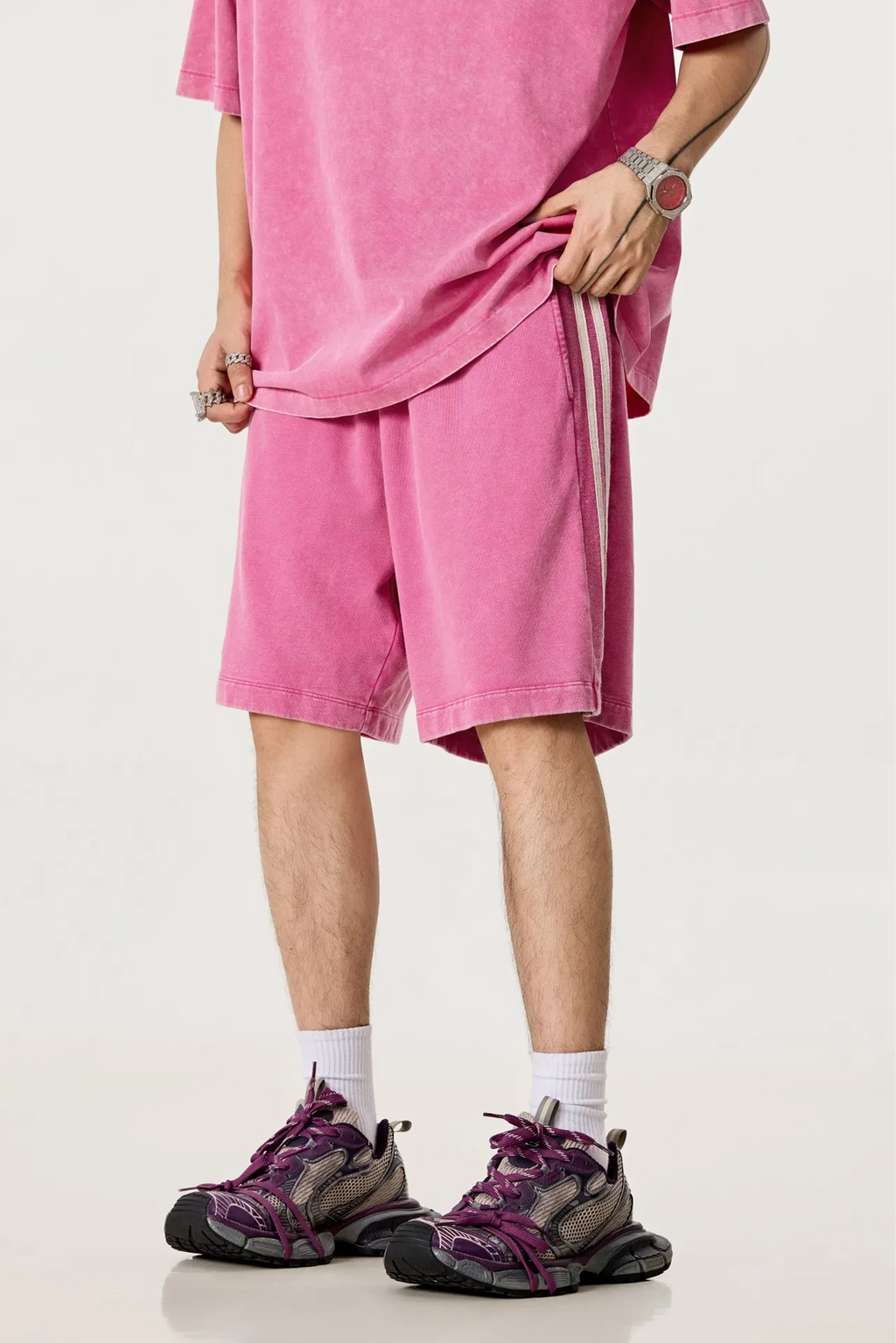 Person wearing a pink outfit with shorts and sneakers on a white background