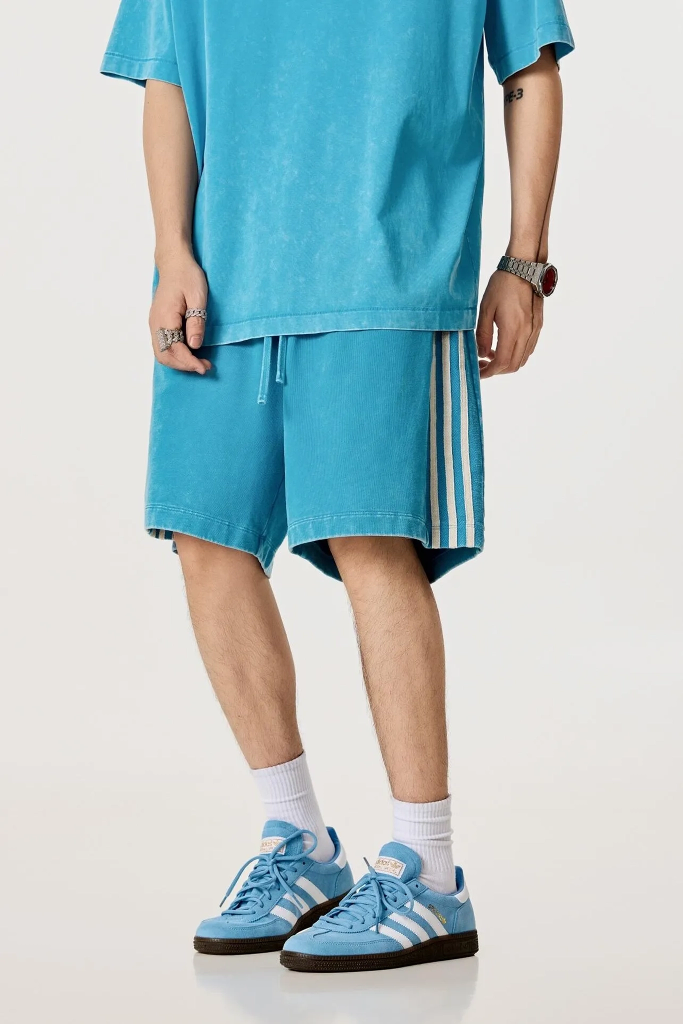 Person wearing a blue outfit with shorts and sneakers on a white background