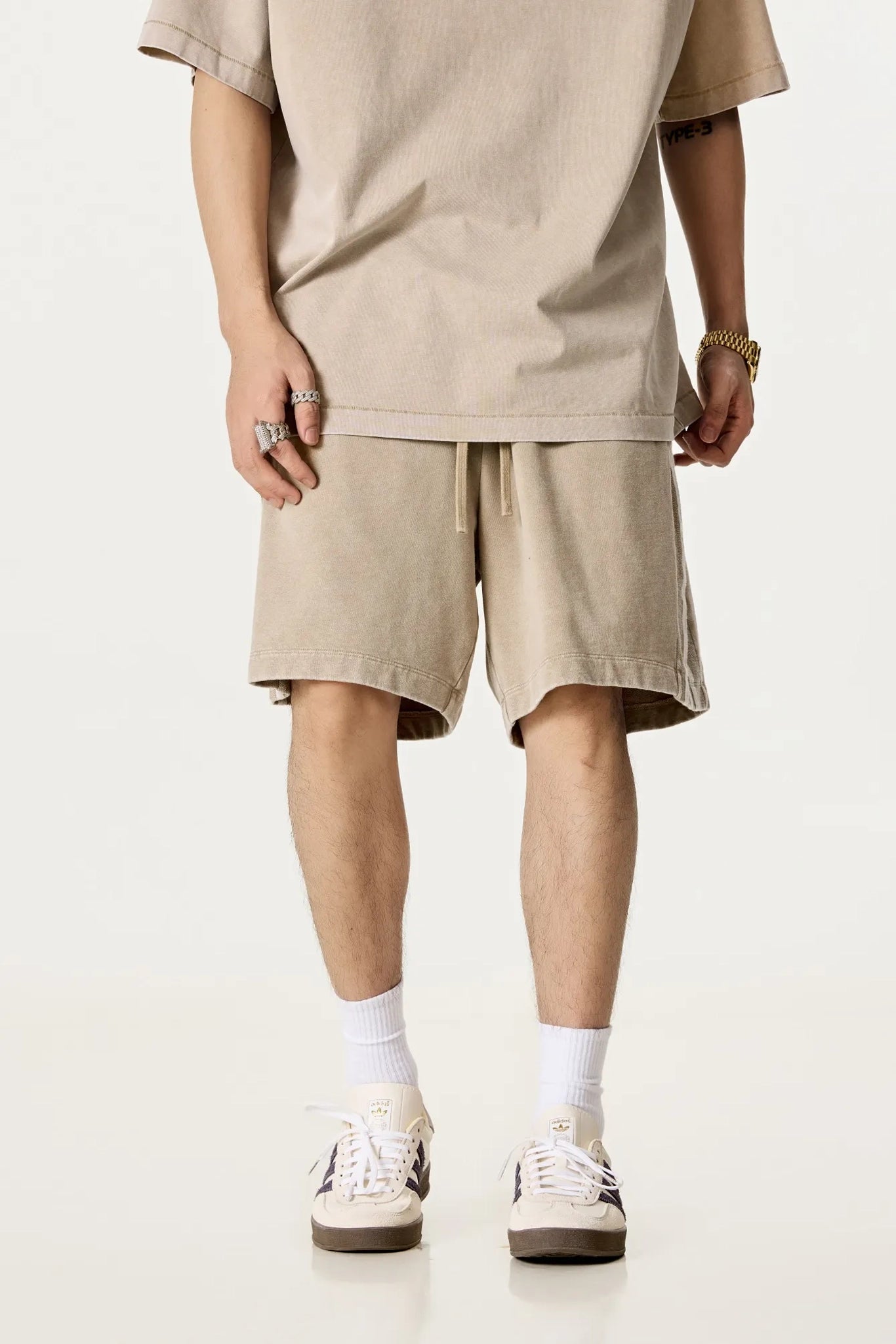 Person wearing beige shorts and a t-shirt on a white background