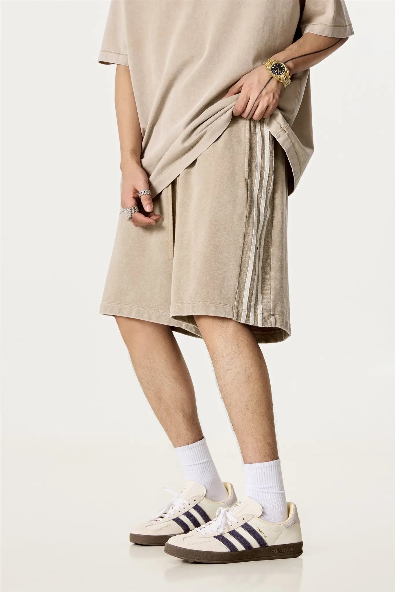 Person wearing a beige dress, white socks, and Adidas sneakers on a white background