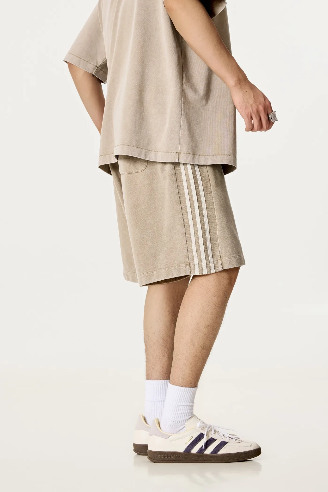 Person wearing a beige outfit with shorts and sneakers on a white background