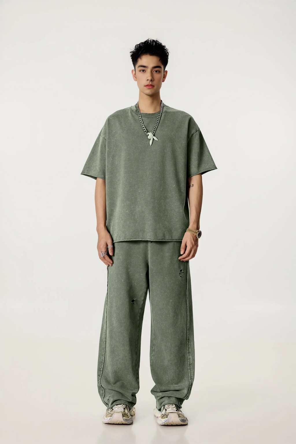 Person wearing a green outfit with a necklace on a white background