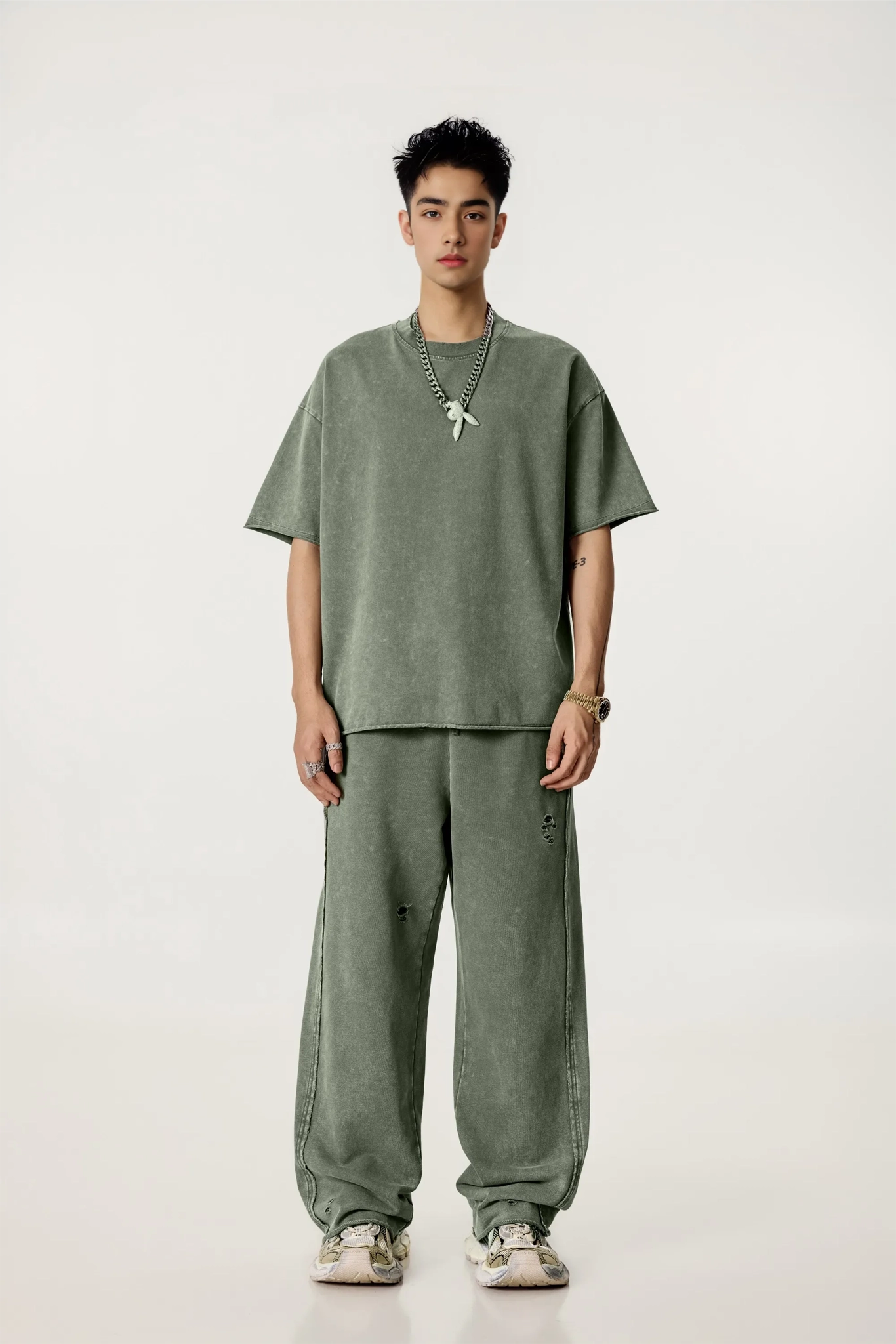 Person wearing a green outfit with a necklace on a white background