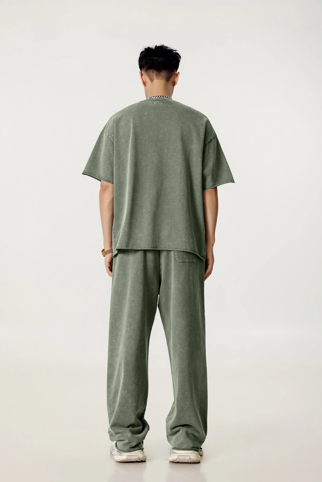 Person wearing a green outfit standing against a white background