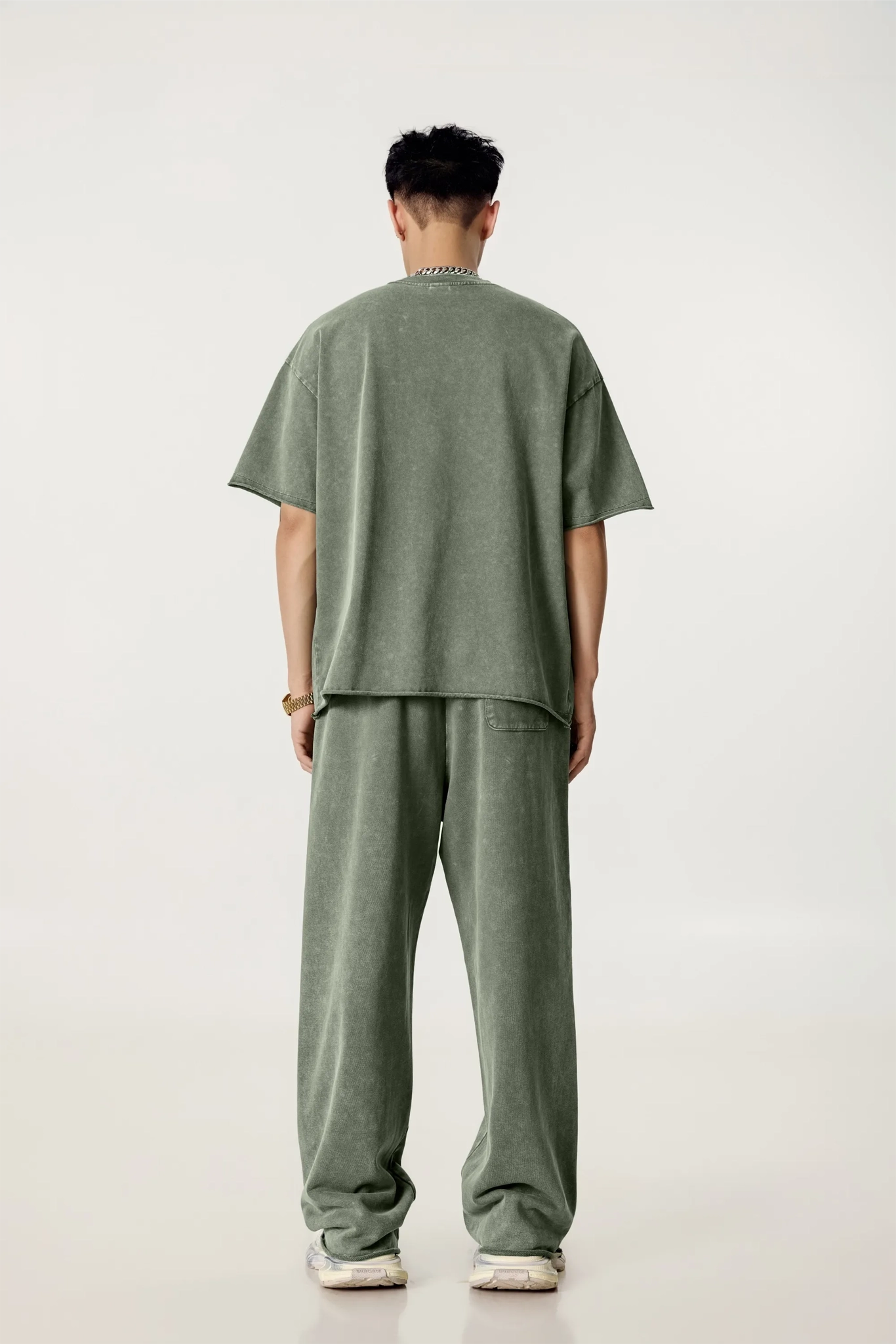 Person wearing a green outfit standing against a white background