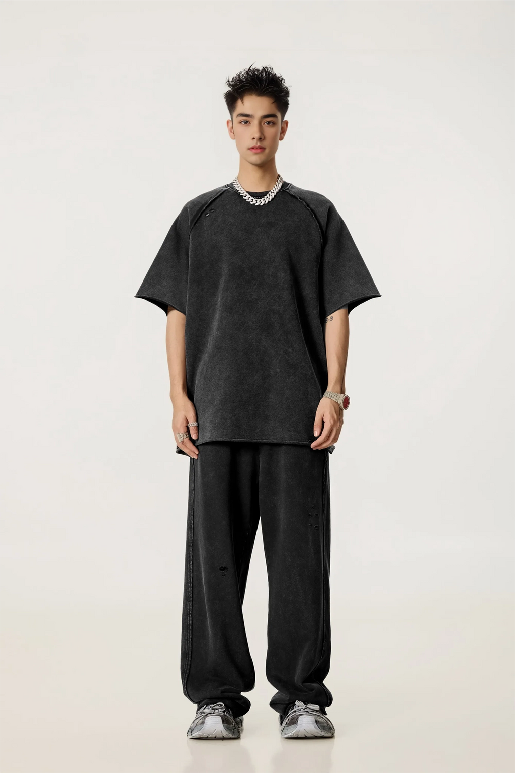 Person wearing a black oversized t-shirt and pants on a white background