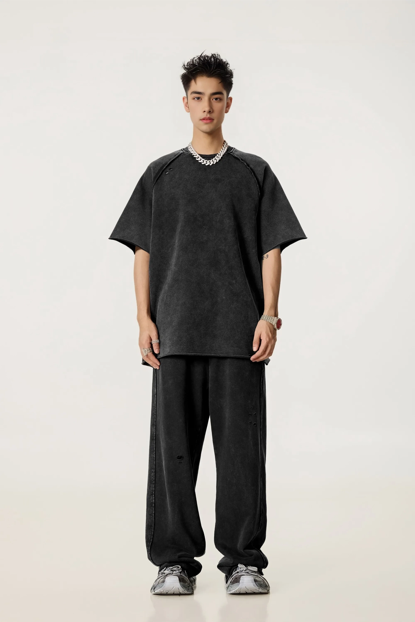 Person wearing a black oversized t-shirt and pants on a white background