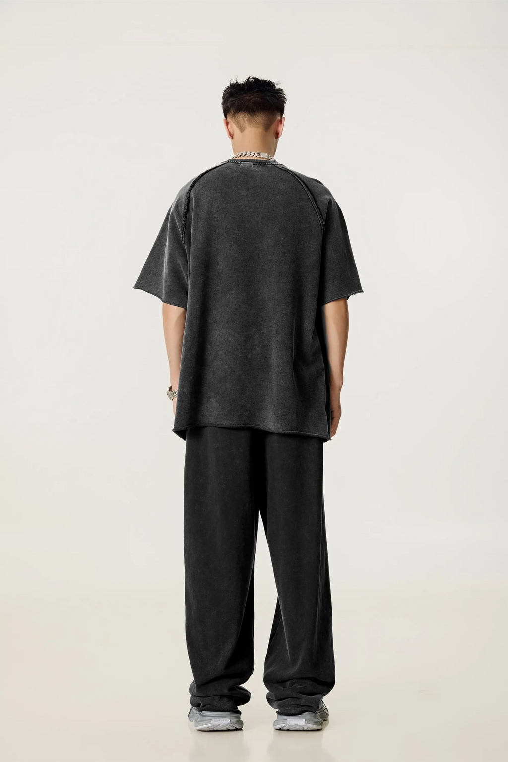 Person wearing a dark oversized t-shirt and pants on a white background