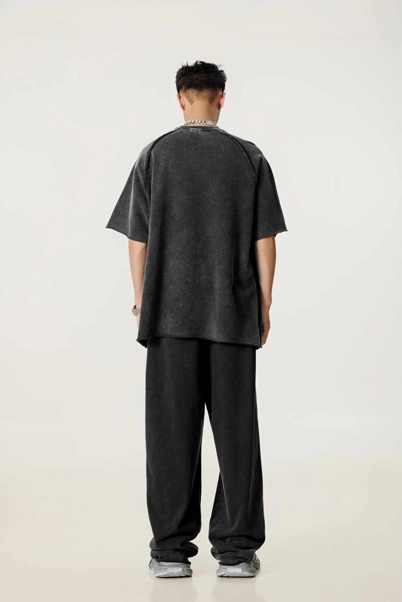 Person wearing a dark oversized t-shirt and pants on a white background