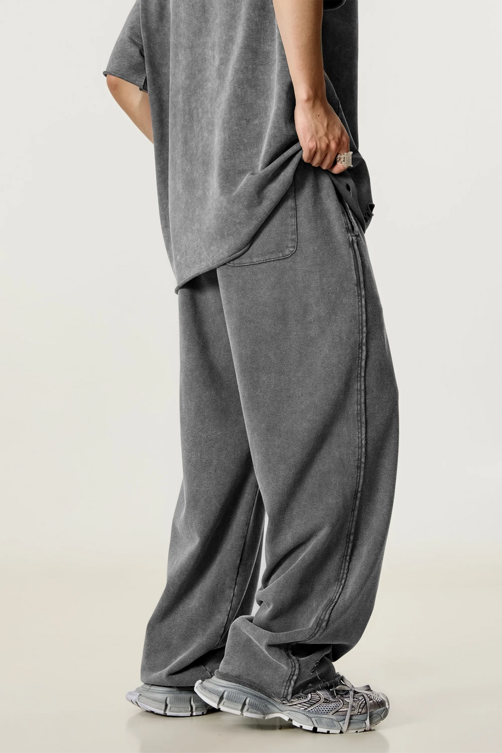 Person wearing a gray oversized t-shirt and wide-leg pants on a light background