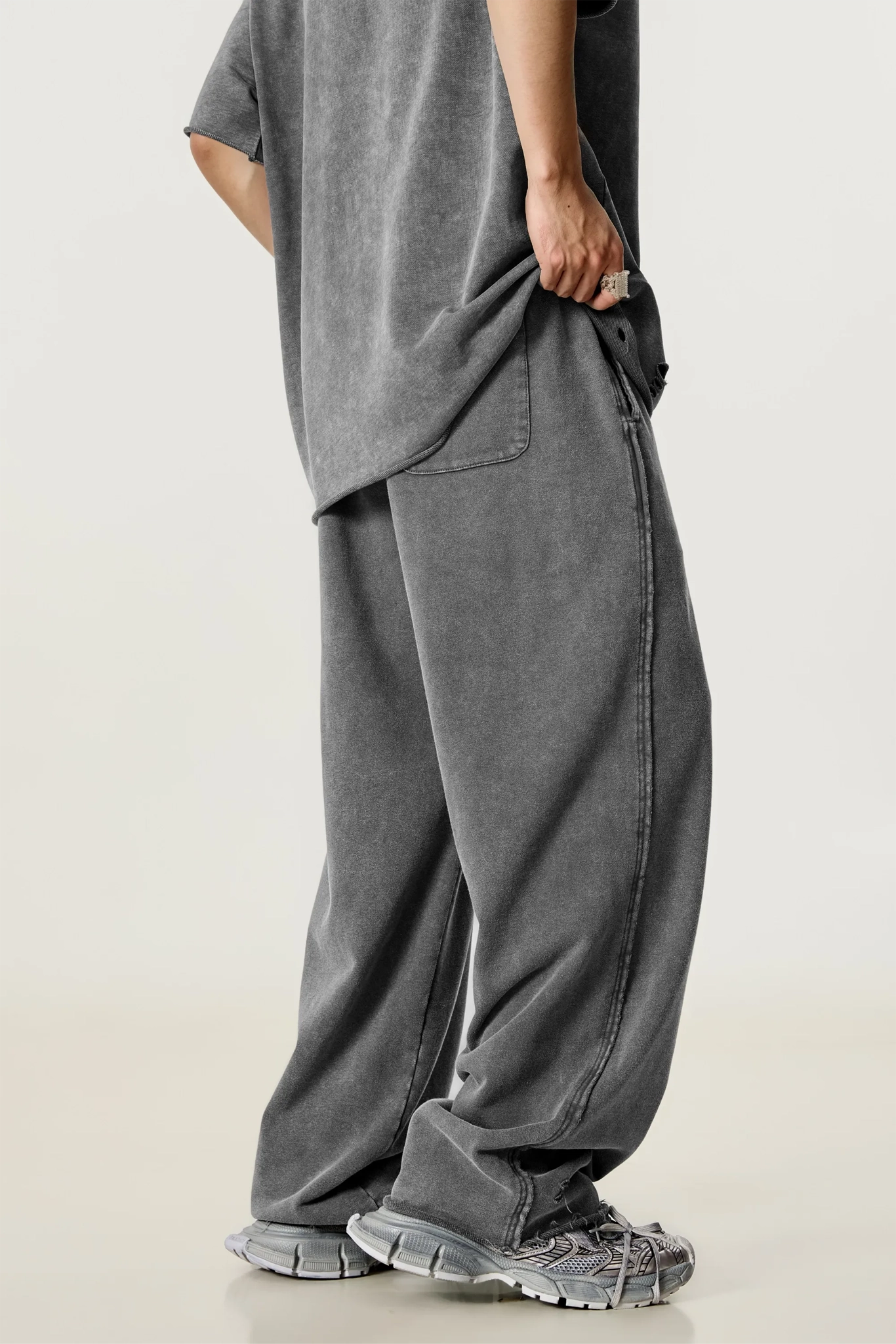 Person wearing a gray oversized t-shirt and wide-leg pants on a light background