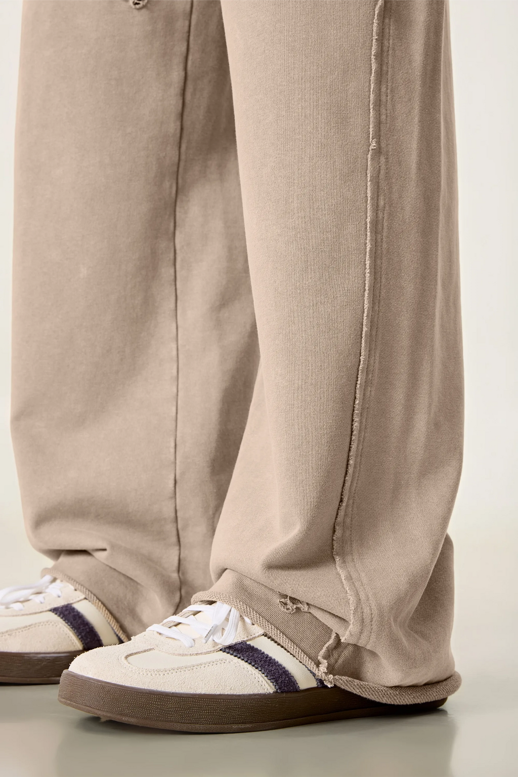 Beige pants and white sneakers with blue accents on a light background