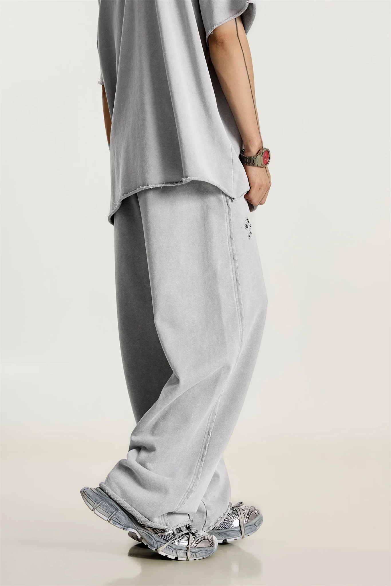 Person wearing a loose-fitting gray outfit with wide-leg pants on a light background